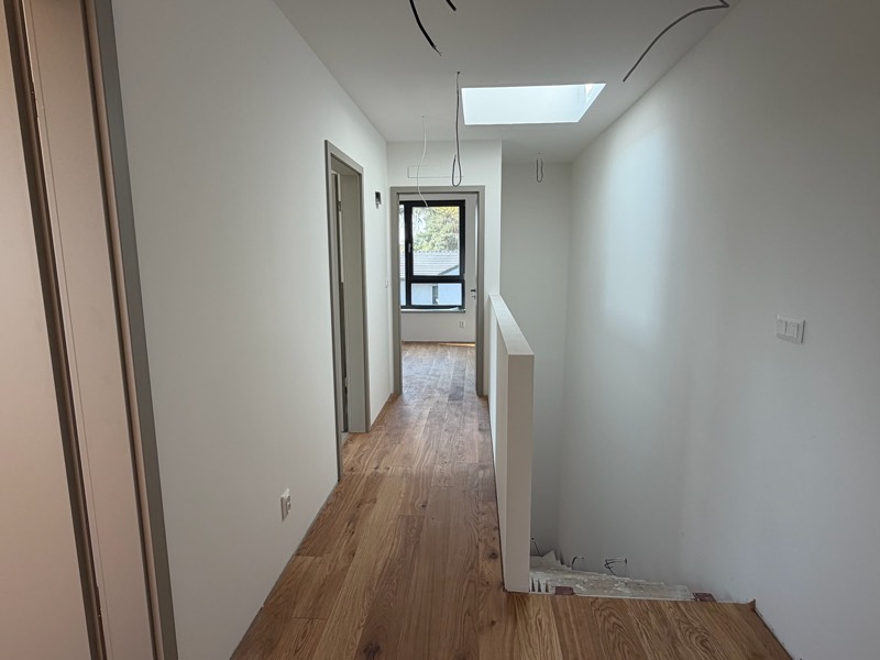 Site photo: upstairs hallway with a skylight, oak flooring and the staircase