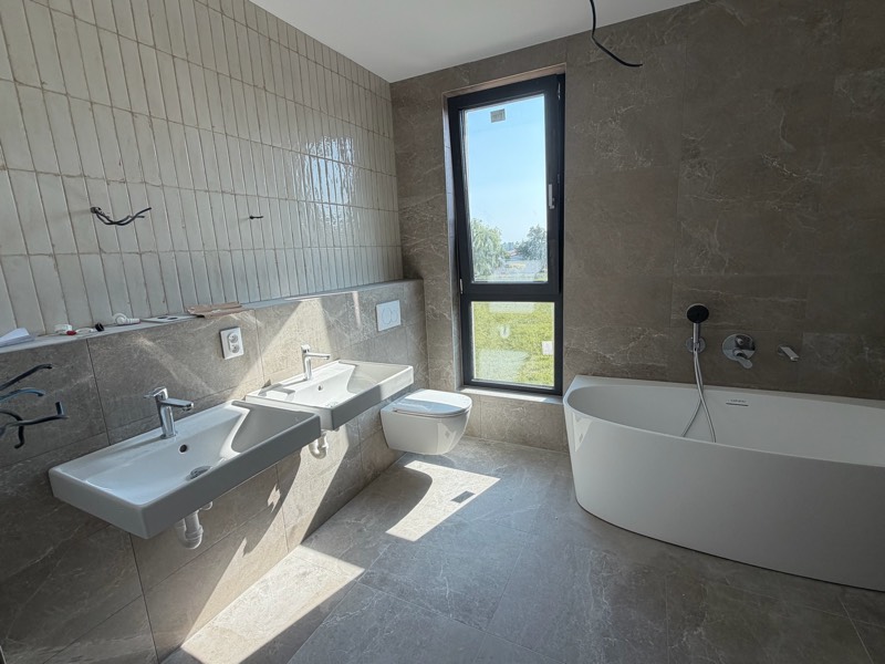 Site photo: bathroom with a freestanding bathtub, two washbasins and large-format tiles