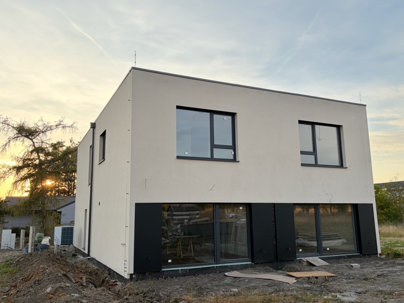 Site photo: the house from the garden at sunset, large glazed windows on the ground floor
